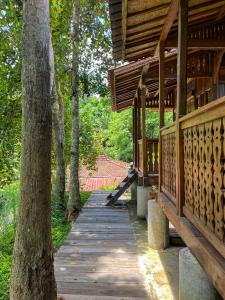 a wooden walkway in a park with a tree at Bidja Room Wooden Joglo House in Sempidi