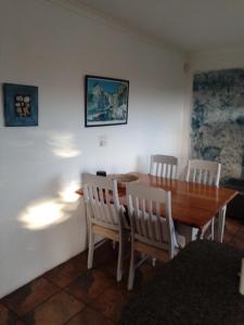a dining room with a wooden table and chairs at Streams Cottage in Bettyʼs Bay