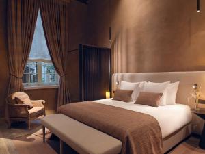 een slaapkamer met een bed, een stoel en een raam bij Botanic Sanctuary Antwerp - The Leading Hotels of the World in Antwerpen