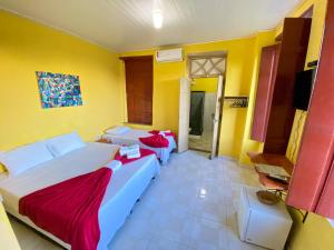 a bedroom with two beds and a yellow wall at Pousada Jardim Lençóis in Lençóis