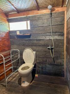 a bathroom with a toilet and a shower at Bidja Room Wooden Joglo House in Sempidi