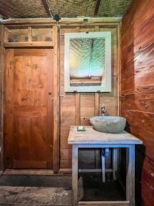 a bathroom with a sink on a wooden wall at Bidja Room Wooden Joglo House in Sempidi