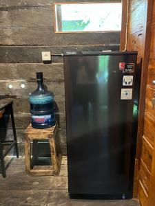 a black refrigerator sitting next to a bottle of water at Bidja Room Wooden Joglo House in Sempidi