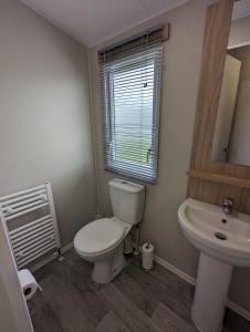 a bathroom with a white toilet and a sink at Stylish Modern Bright Caravan with Views sleeps 6 Littlesea Haven Weymouth in Weymouth