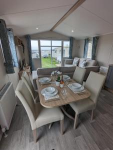 a dining room and living room with a table and chairs at Stylish Modern Bright Caravan with Views sleeps 6 Littlesea Haven Weymouth in Weymouth