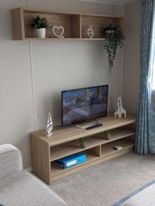 a living room with a television on a wooden entertainment center at Stylish Modern Bright Caravan with Views sleeps 6 Littlesea Haven Weymouth in Weymouth