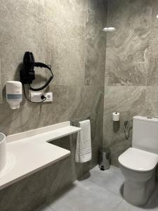 Un baño con inodoro y un teléfono en la pared. en Almar 52 Suites, en Valencia 38 fotos más