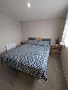 a bedroom with a bed with a blue and white comforter at Stylish Modern Bright Caravan with Views sleeps 6 Littlesea Haven Weymouth in Weymouth