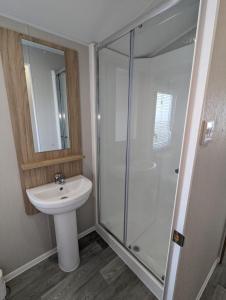 a bathroom with a glass shower and a sink at Stylish Modern Bright Caravan with Views sleeps 6 Littlesea Haven Weymouth in Weymouth