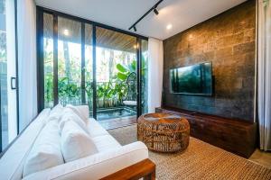 ein Wohnzimmer mit einem weißen Sofa und einem TV in der Unterkunft The Hitam Tiny Villa - 2 BR Architectural Villa 4 mins to Beach in Tanah Lot
