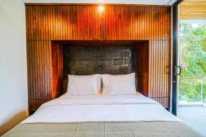 Bett in einem Zimmer mit einer Holzwand in der Unterkunft The Hitam Tiny Villa - 2 BR Architectural Villa 4 mins to Beach in Tanah Lot