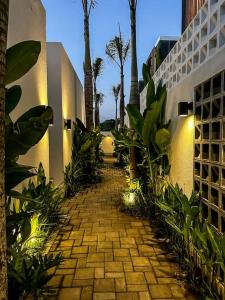einen Backsteinweg mit Palmen und einem Gebäude in der Unterkunft The Hitam Tiny Villa - 2 BR Architectural Villa 4 mins to Beach in Tanah Lot