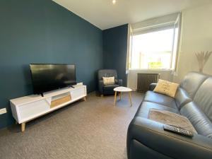 uma sala de estar com um sofá e uma televisão de ecrã plano em Appartement neuf de type 3 em Soyaux