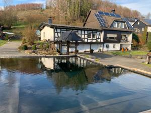 una casa con una piscina de agua frente a ella en Zur Clemens Hütte en Drolshagen