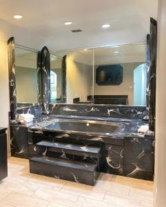 a bathroom with a black tub and a large mirror at Island Suites Hobby Airport in Houston