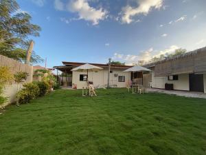 a yard with chairs and umbrellas in front of a house at Mingche Apartment in Panglao Island