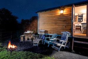 un patio trasero con 2 sillas y una hoguera en Teasel Shepherd's Hut, en Berwick-Upon-Tweed