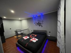 1 dormitorio con cama negra y luces azules en Fabianna suite, en Agliano Terme