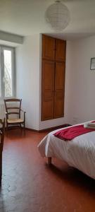 a bedroom with a bed and a chair in a room at Chambres d'Hôtes, Domaine Les Peupliers in Lagnes