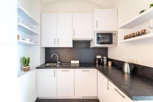 una cucina bianca con mobili bianchi e un lavello di Neat Studio Steps to Center by HM a Vienna