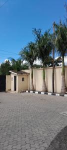 a row of palm trees in front of a wall at Twiga Whitehouse Villas in Nakuru
