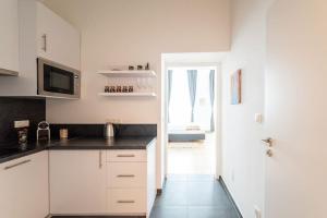 una cucina con armadi bianchi e piano di lavoro nero di Neat Studio Steps to Center by HM a Vienna Altre 9 foto