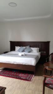 a bedroom with a large bed with a wooden headboard at Twiga Whitehouse Villas in Nakuru
