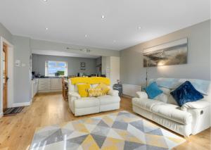 a living room with two white couches and a kitchen at Benone Getaways in Derry Londonderry