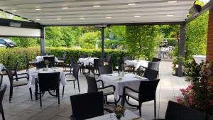 a restaurant with white tables and chairs on a patio at Hotel Restaurant Teichaue in Adendorf