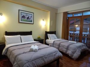 um quarto de hotel com duas camas e uma janela em Hospedaje "LOS QUETZALES DE OXAPAMPA" em Oxapampa