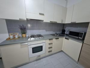 uma cozinha com armários brancos e um forno com placa de fogão em Casa Amelia lago Maggiore em Maccagno Inferiore