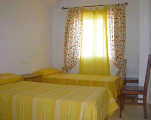a bedroom with two beds and a window with curtains at Acogedor apartamento con vistas al Mediterráneo. in Mojácar