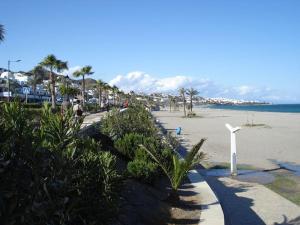 a sandy beach with palm trees and a white pole at Acogedor apartamento con vistas al Mediterráneo. in Mojácar