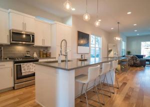 a kitchen with white cabinets and a large island with bar chairs at Beautiful New Home Downtown SXSW ACL F1 HQ in Austin