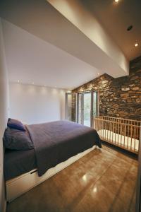 1 dormitorio con cama y pared de piedra en La Bella Villa, en Melínta