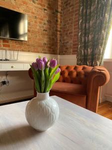 biała waza z fioletowymi kwiatami na stole w obiekcie Apartments PSD - Anny Łajming 1B w mieście Słupsk