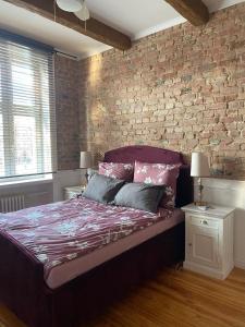 a bed in a bedroom with a brick wall at Apartments PSD - Anny Łajming 1B in Słupsk