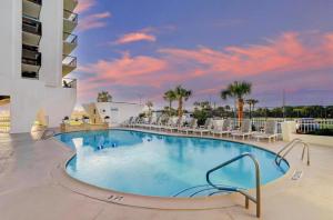 a large swimming pool in a resort with chairs at Beachfront Islander East Studio in Galveston