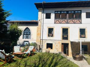 un edificio blanco con ventanas y sillas en un patio en Casa Arenas, en Arenas de Cabrales