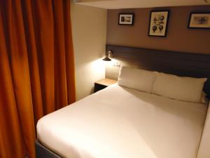 a bedroom with a white bed with an orange curtain at Almondsbury Inn & Lounge in Almondsbury