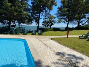 a woman standing next to a swimming pool next to a park at Troia Apartments in Troia