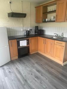 uma cozinha com armários de madeira e electrodomésticos pretos em Kickham Street Budget Accommodation em Carrick-on-Suir