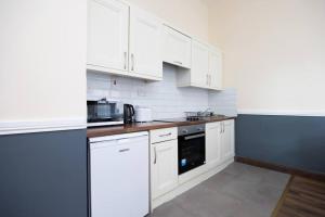 une cuisine avec des armoires blanches et un appareil noir dans l'établissement Homely 1 bedroom apartment in Smithfield, Dublin, à Dublin