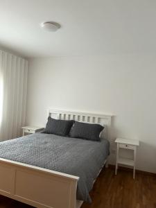 a white bedroom with a bed and two tables at Beach House in Vila do Conde