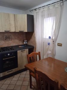 加埃塔的住宿－Dea's House con parcheggio，厨房配有木桌、餐桌和窗户。