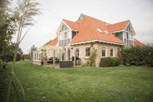a house with an orange roof on a green yard at Waddenvilla 18 in Hollum