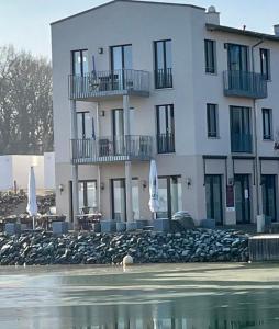 un gran edificio blanco con balcón junto a una masa de agua en Frischer Wind am Hainer See Kahnsdorf, en Neukieritzsch