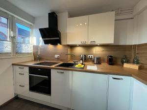 a kitchen with white cabinets and a sink at Zentrales 2-Zi Apartment by Rabe - Kirche - Coffee-Bar in Karlsruhe