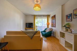 ein Wohnzimmer mit einem Sofa und einem Stuhl in der Unterkunft Le Concerto - Appartement à 5 min de Vannes in Plescop