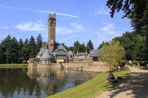 a large building with a clock tower next to a lake at Natuurhuisje in Otterlo